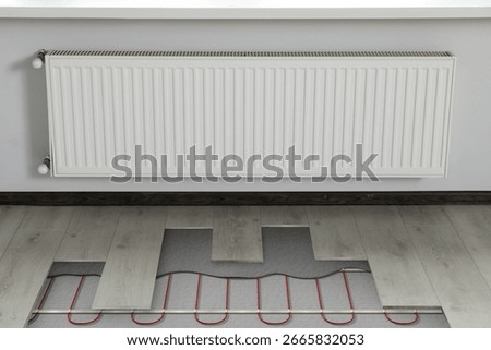 Underfloor heating system installed in room. Pipes seen under laminate