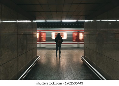 Underground arrives at the station while a woman is waiting in the city centre of Prague in the Czech Republic. Motion blur blue green and red. Public transport Europe.