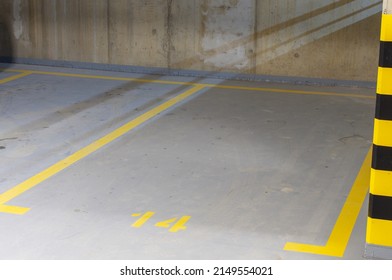 Underground car park. Empty garage, parking lot with yellow black markings on the pillars. Numbered parking spaces.