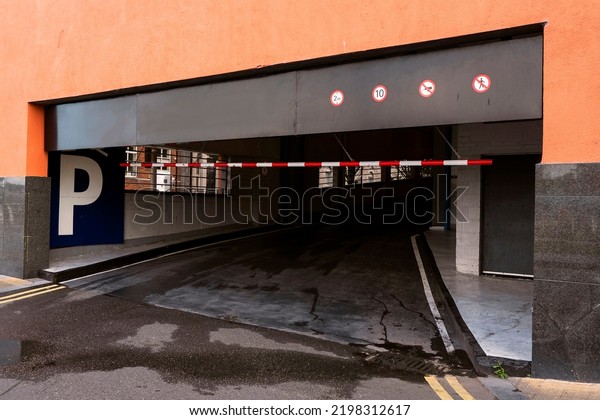 Underground car park entrance in a street of a\
residential or office building with P white sign on blue background\
and arrow. Urban\
life.
