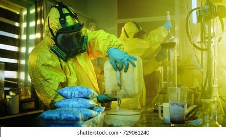 In the Underground Drug Laboratory Clandestine Chemists Wearing Protective Masks and Coveralls Mix Chemicals. One Pours Liquid From Canister into Bowl, Second Checks Beaker for Product Consistency.