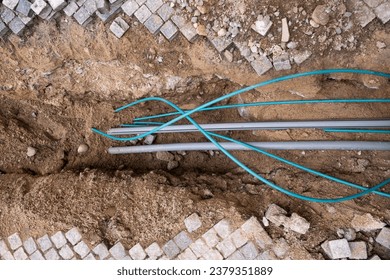 Underground electric cable infrastructure communication installation at a construction site with various cables protected in tubes. High-speed internet network cables are buried underground