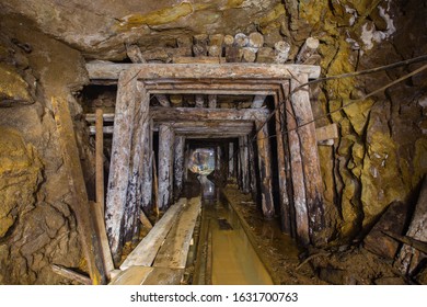 Underground gold mine shaft tunnel drift with rails and wooden timbering