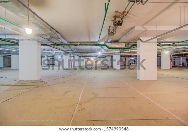 Underground parking in construction phase. Empty\
garage in basement of office building under construction. Parking\
without cars. Reinforced concrete monolithic walls in basement of\
house before repair