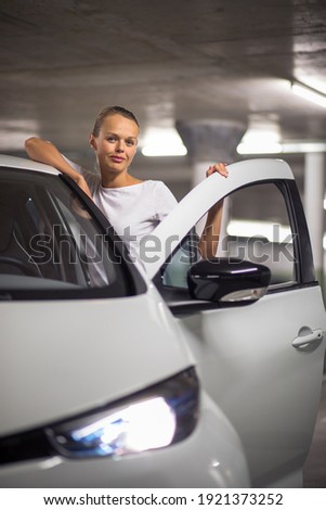 Underground parking, garage (shallow DOF; colour toned image) - young woman with her car in the underground parking