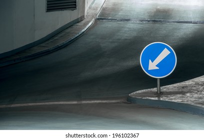 Underground parking level with direction to the left on blue sign with white arrow