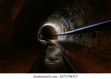 Underground vaulted urban sewer tunnel with dirty sewage.