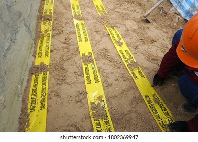 Underground Warning Tape Placed On The Sand To Alert The Underground Power Lines In The Chemical Plant Construction Project.