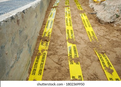 Underground Warning Tape Placed On The Sand To Alert The Underground Power Lines In The Chemical Plant Construction Project.