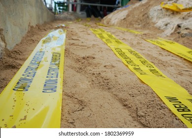 Underground Warning Tape Placed On The Sand To Alert The Underground Power Lines In The Chemical Plant Construction Project.