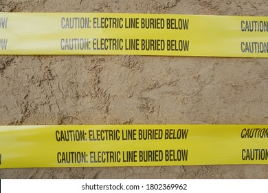 Underground Warning Tape Placed On The Sand To Alert The Underground Power Lines In The Chemical Plant Construction Project.