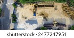 Underground work to install large gas tanks at fuel station construction site, Coppell, Texas, aerial view backhoe crawler excavator, dump truck, bulldozer digging busy parking lot grocery store. USA