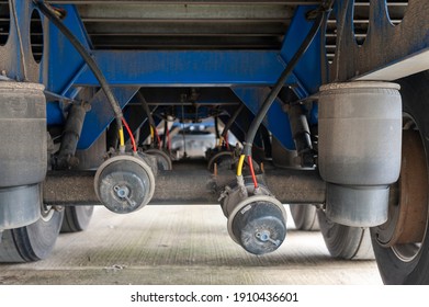 Underneath View Of A Semi Trailer Showing The Three Axles And Air Bags And Brake Chambers With One Of The Offside Rear Broken Off The Axle With Shallow Focus.