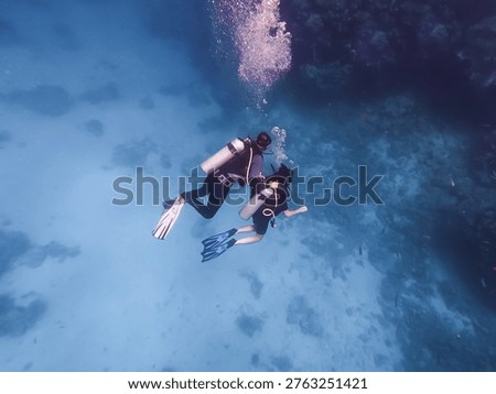Undersea view of a certified instructor training a young woman student how to scuba dive in the Red Sea Egypt.