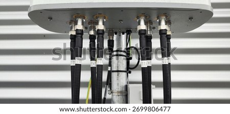 Underside of a cellular sector antenna showing many RF connectors and black coax cables on a rooftop installation.