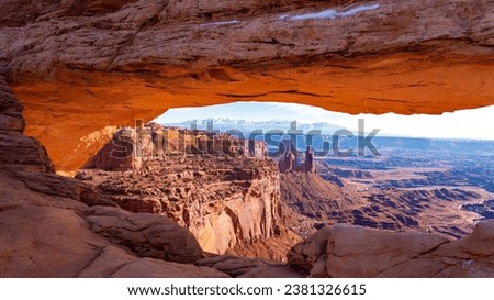 The underside of Mesa Arch glows in the early morning light. The panoramic view over Buck Canyon with Washerwoman Arch in front of Airport Tower and Monster Tower to the right. 