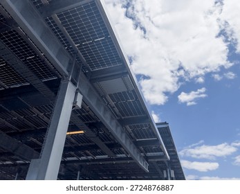 Underside view of elevated solar panel structure against blue sky