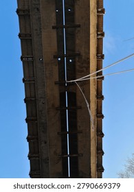 Underside of weathered concrete bridge structure photographed from below against blue sky