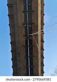 Underside of weathered concrete bridge structure photographed from below against blue sky