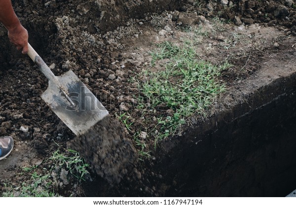 Undertaker shovels the soil to cover\
the grave and bury the dead.  Selective focus. Copy\
space.