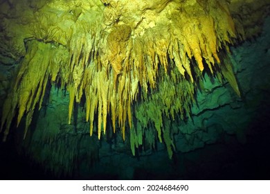 Underwater cave with stalactites.  Photography from scuba diving in flooded cave, extreme exploration. Cenote ceiling and limestone decoration. Dark space in freshwater cavern.