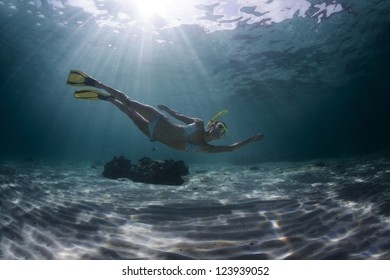 Underwater Full Length Portrait Of A Woman Snorkeling In Tropical Sea Over Sandy Bottom