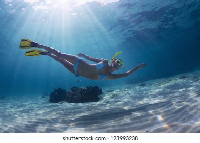 Underwater Full Length Portrait Of A Woman Snorkeling In Tropical Sea Over Sandy Bottom