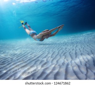 Underwater Full Length Portrait Of A Woman Having Fun In A Tropical Sea Over Sandy Bottom