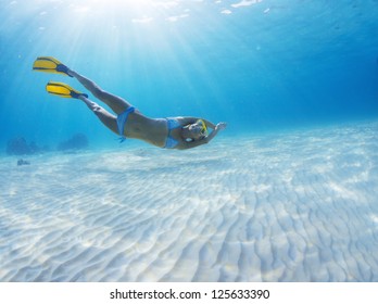 Underwater Full Length Portrait Of A Woman Having Fun In A Tropical Sea Over Sandy Bottom