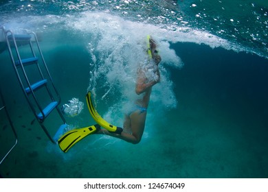 Underwater Full Length Portrait Of A Young Lady Jumping Into A Tropical Sea From A Boat