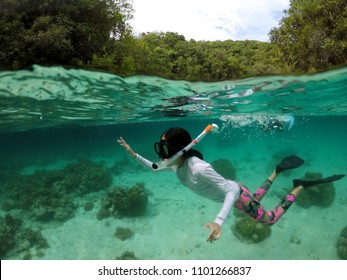 Underwater healthy active young girl enjoy snorkeling with mask, snorkel and fin. Asian teenager girl skin diving under water over beautiful coral reef on summer vacation, Micronesia, Nikko bay, Palau