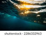 Underwater photo from beneath a wave sparkling from the sunset. Aqua water mixed with golden sunset.