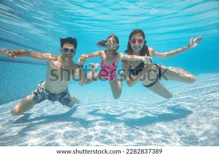 underwater photo of big  family with little kids  swimming  in pool