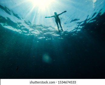 Underwater photo of woman floating in the sea and rays of light piercing through
