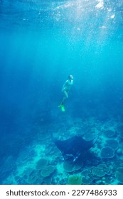 Foto submarina de una joven mujer buceando en un agua tropical clara con manta raya en Maldivas