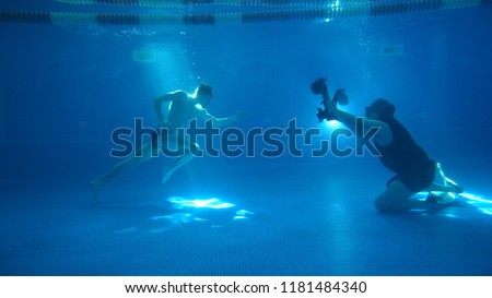 Underwater photography. A male model is posing underwater. A young handsome man is running along the bottom. Behined the scenes. Making of.