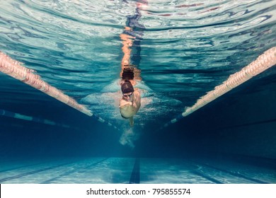 underwater picture of young swimmer in cap and goggles training in swimming pool - Shutterstock ID 795855574