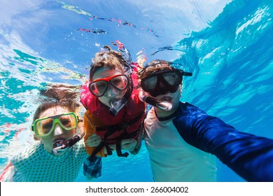 Underwater Portrait Of Family Snorkeling Together At Clear Tropical Ocean