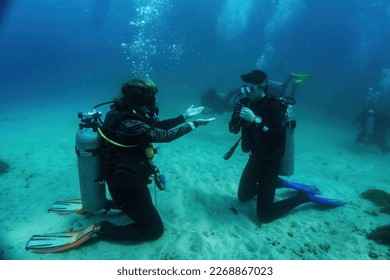 Underwater Scuba dive course training. Unidentified dive master explains with gestures what has to be done during the underwater dive lesson. Bali, Indonesia