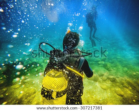 Man in his back with scuba diving equipment exploring the ocean floor.