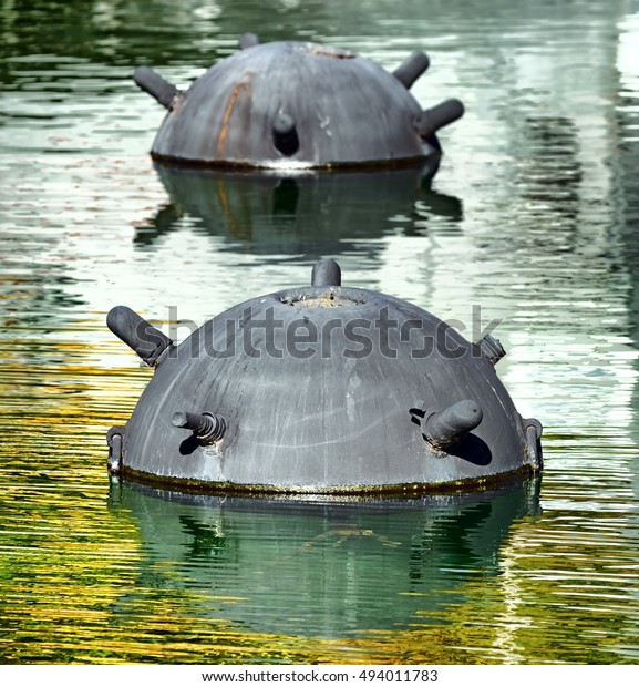 underwater sea mine military anti\
warship weapon war shield half body visible out of water surface\
reflections weathered detail exterior vertical war scene theme\
view