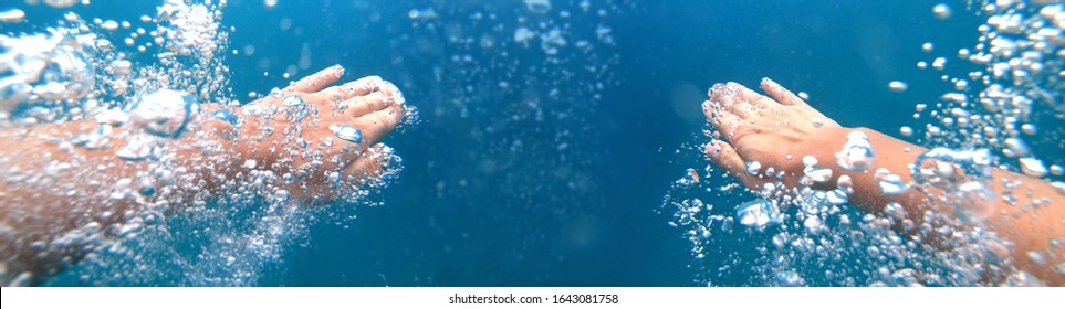 Underwater shoot of a diver swimming in a blue clear water, strong hands and lots of bubbles. Point of view shot - Powered by Shutterstock