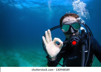 Underwater shoot of a man diving with scuba and showing ok signal