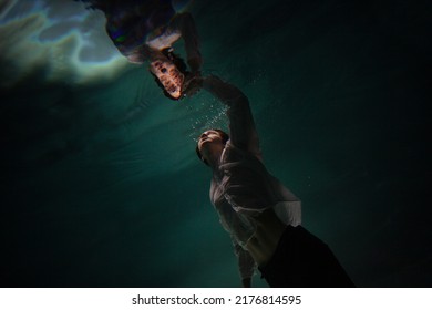 underwater shooting with contrasting light, a guy is swimming underwater, pulling his hand to his reflection in the surface of the water. Subconsciousness and self-reflection, concept - Shutterstock ID 2176814595