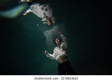 underwater shooting with contrasting light, a guy in a white shirt and pants screaming underwater, panicking and afraid of drowning, falling into the water, a crime. - Shutterstock ID 2176814615
