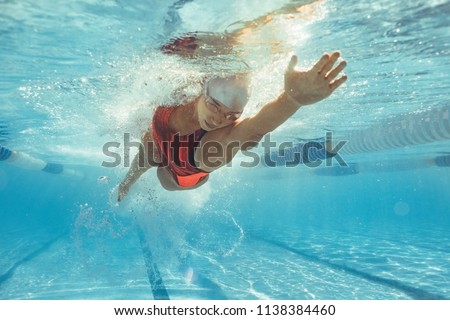 Underwater shot of female athlete swimming in pool. Young woman swimming the front crawl in a pool.