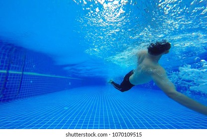 Underwater Shot Of Fit Swimmer Training In The Swimming Pool.Amateur Male Swimmer Practicing Inside The Club House Pool.Sport , Health Care Concept.