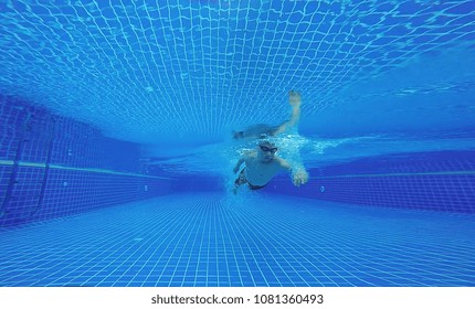 Underwater Shot Of Fit Swimmer Training In The Swimming Pool.Amateur Male Swimmer Practicing Inside The Club House Pool.Sport , Health Care Concept.Copy Space For Text.