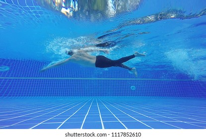 Underwater Shot Of Fit Swimmer Training In The Swimming Pool.Amateur Male Swimmer Practicing Inside The Club House Pool.Sport , Health Care Concept.Copy Space For Text.