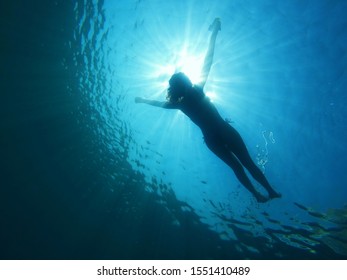 underwater shot of a girl floating on water under the sun - Powered by Shutterstock